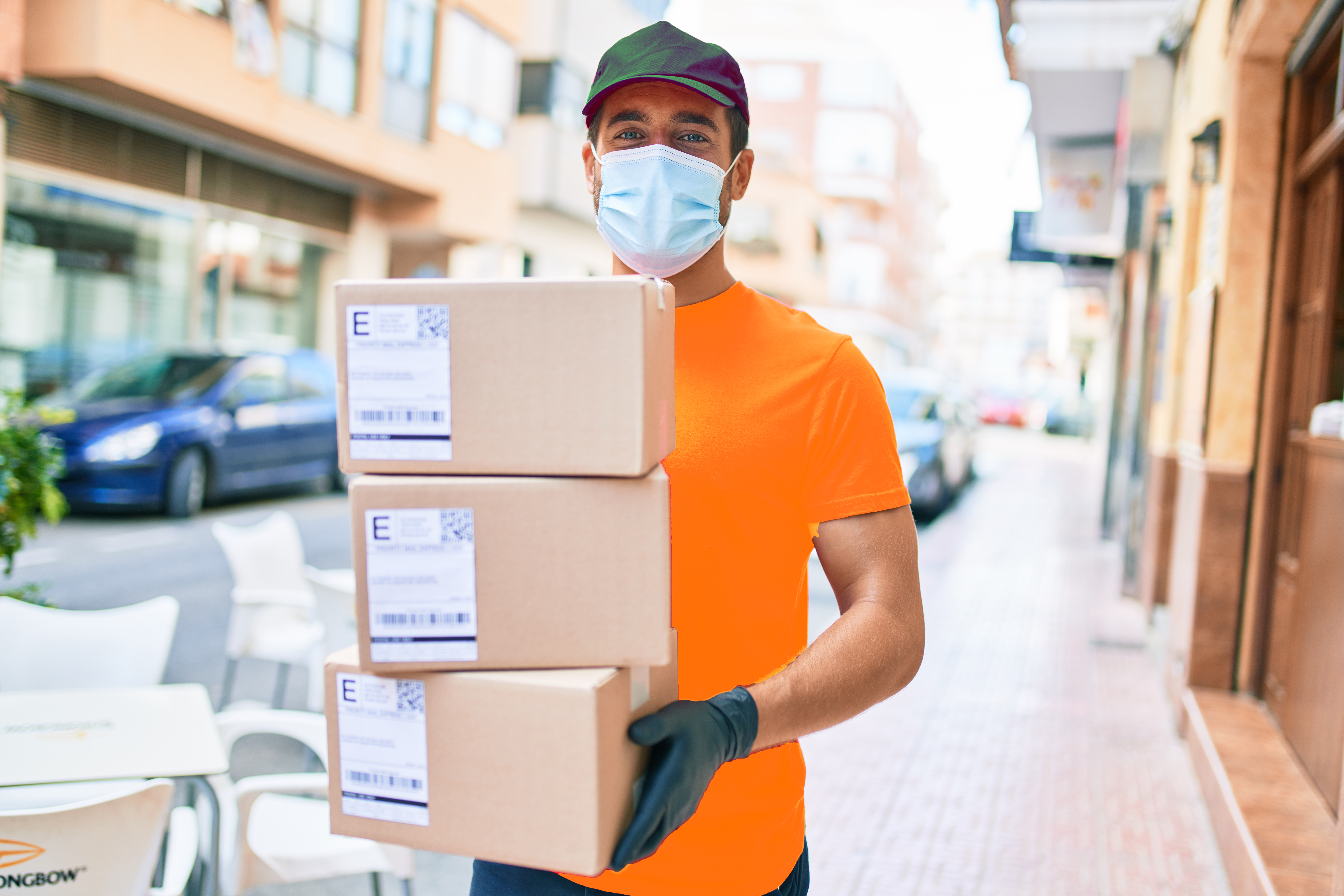 a delivery man in the street posing carrying three boxes