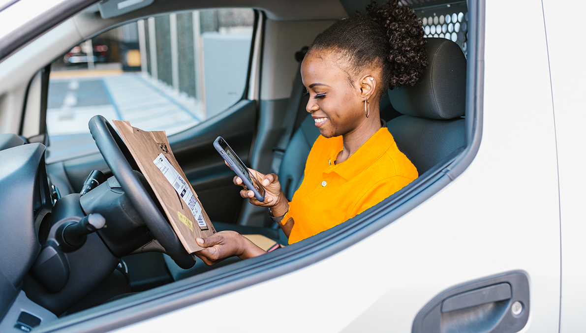 a delivery woman looking to a package inside her van